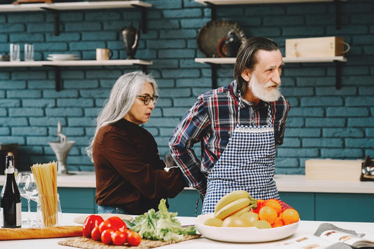 un couple de personnes âgées s'entraide pour préparer a manger dans leurs cuisine