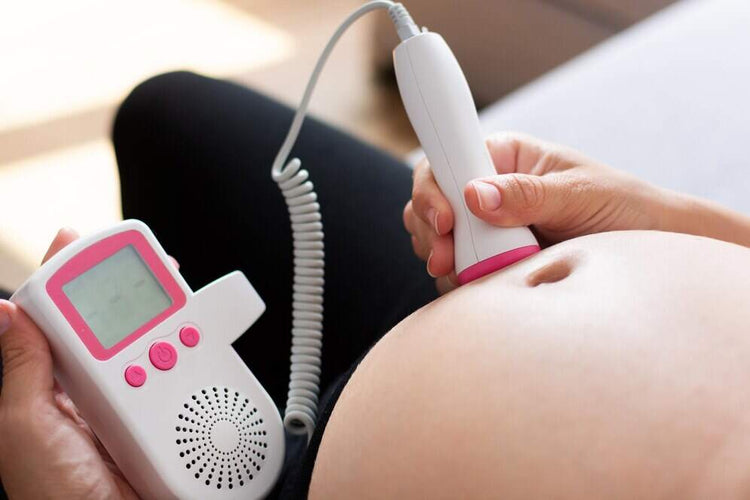 une femme enceinte qui écoute le cœur de son bébé avec un doppler