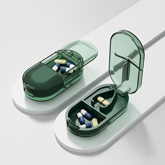 Coupe comprimé pilulier "MediCut Pro" de couleur vert transparent posé sur une barre grise sur fond blnc