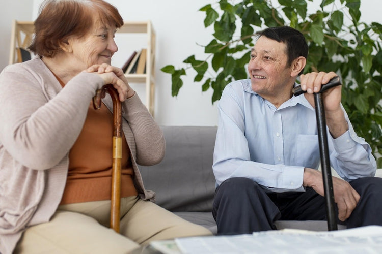 deux senior en train de discuter dans un canapé qui tiennent leur canne de marche pour senior .