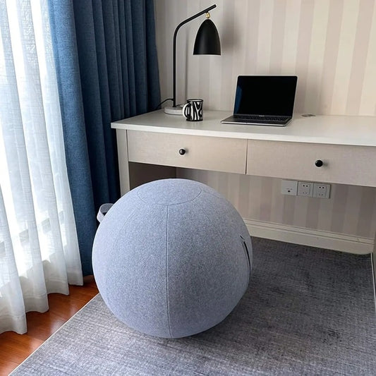 une swiss ball dans sa housse d'habillage gris qui sert de fauteuil devant un bureau design